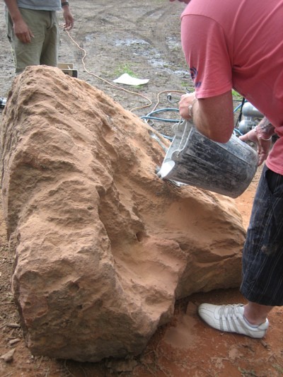 Expando being poured into drilled holes in a large rock